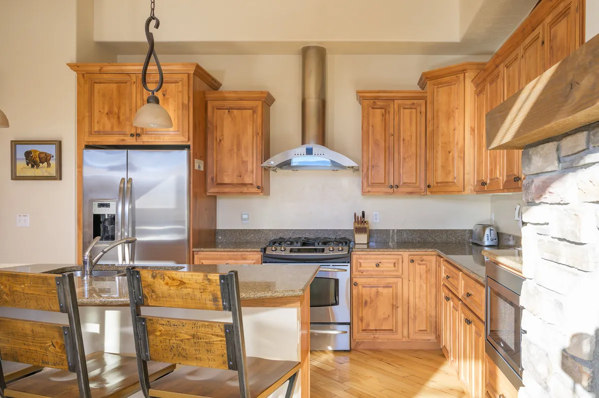 A cozy kitchen scene with wooden cabinetry, stainless steel appliances, granite countertops, and an island that includes casual seating. The setting is warm and inviting, perfect for family meals and celebrations.