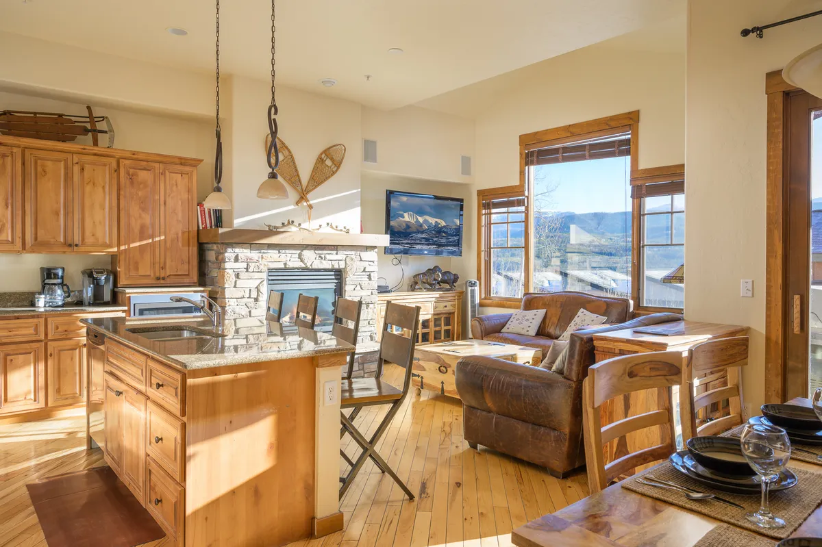 A bright, comfortable great room with a kitchen island, fireplace, and ample seating. Large windows flood the space with natural light, and the open layout encourages socializing and relaxation, making it ideal for shared activities and quiet moments alike.